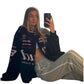 Person wearing a navy jacket with various logos, sitting and taking a selfie.