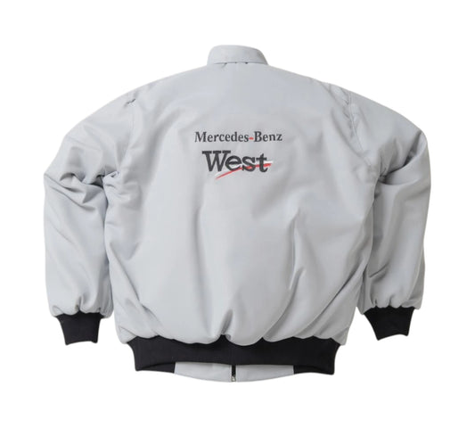 Gray bomber jacket with Mercedes-Benz and West logos on a white background