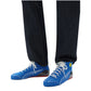 Blue high-top sneakers with white laces and a red sole worn with black pants on a white background.