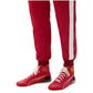 Red tracksuit with white stripes and matching red shoes on a white background
