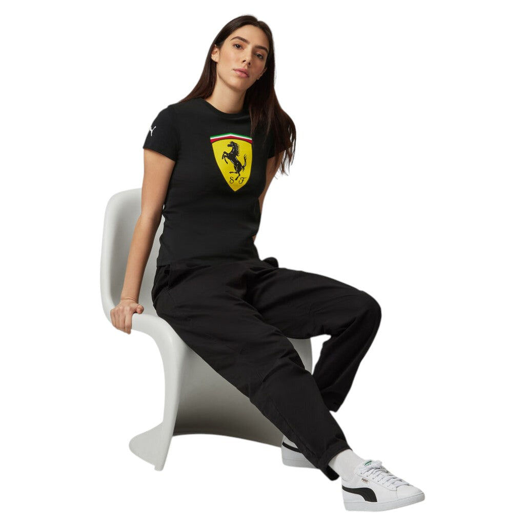 Woman wearing a black Ferrari t-shirt and pants sitting on a white chair.
