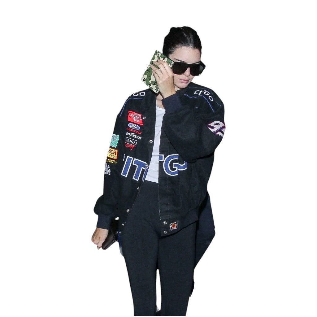 Person wearing a black jacket with various logos on a white background