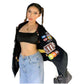 Person wearing a black varsity jacket with logos, black crop top, and blue jeans on a white background